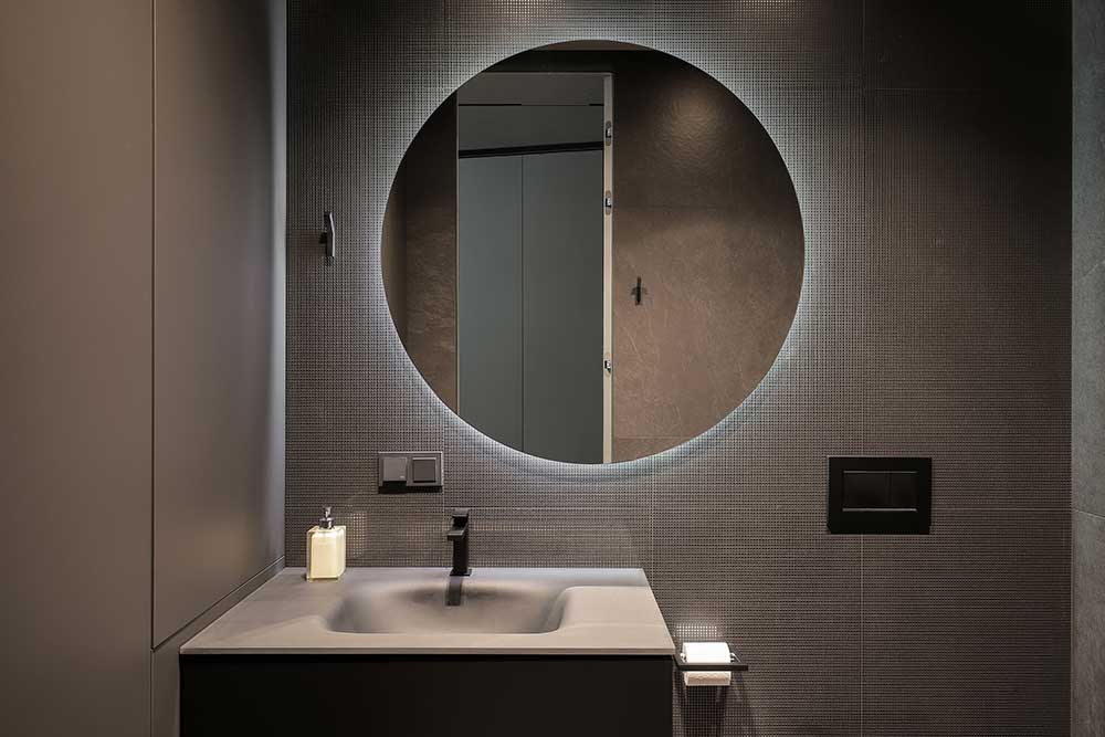 round bathroom mirror with glowing light behind it