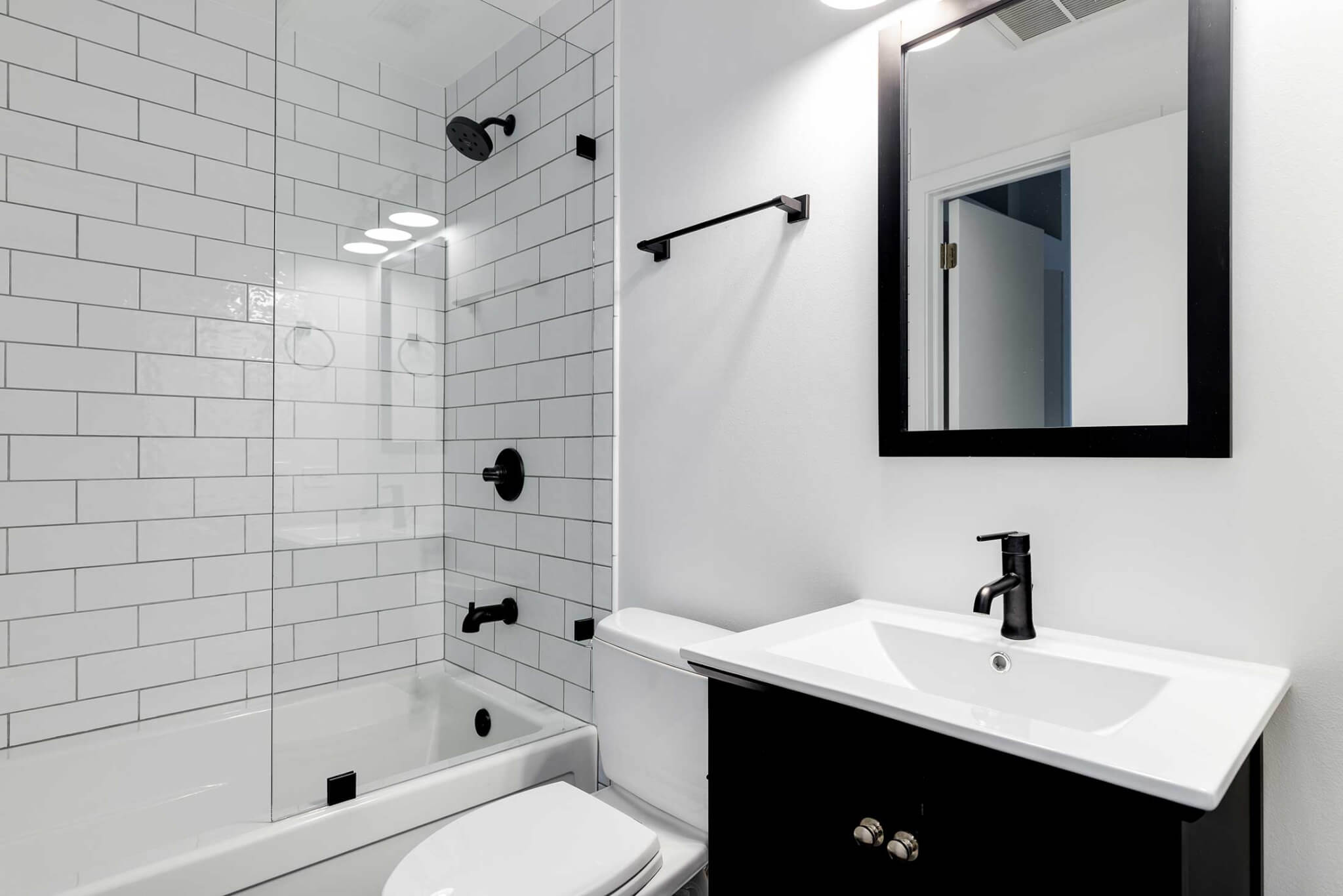 glass shower door in white and black themed bathroom